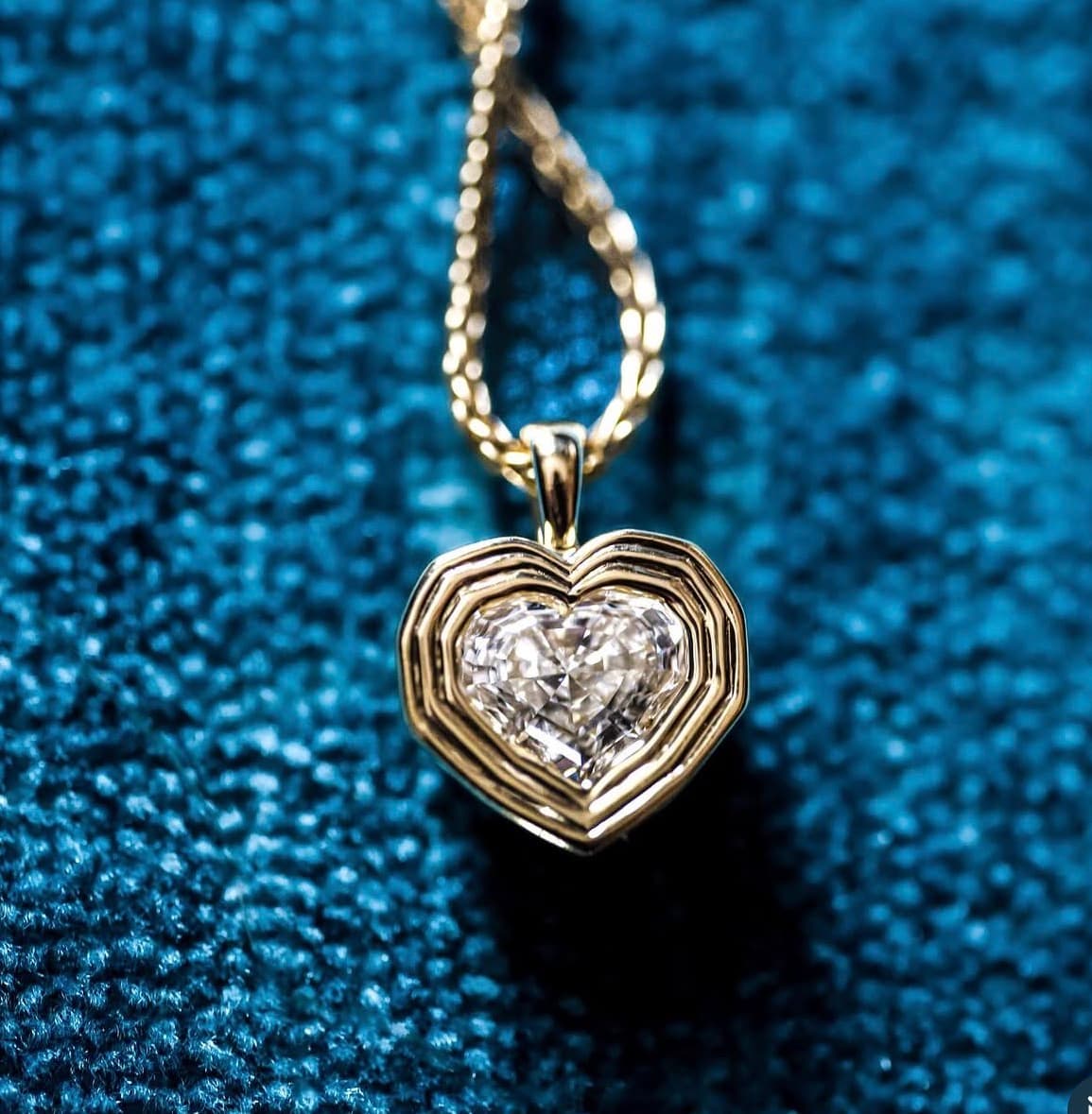 Bespoke gold heart pendant set with a brilliant diamond on a deep blue velvet ground